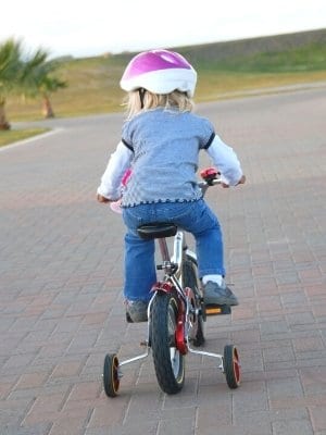 Child riding bicycle with training wheels