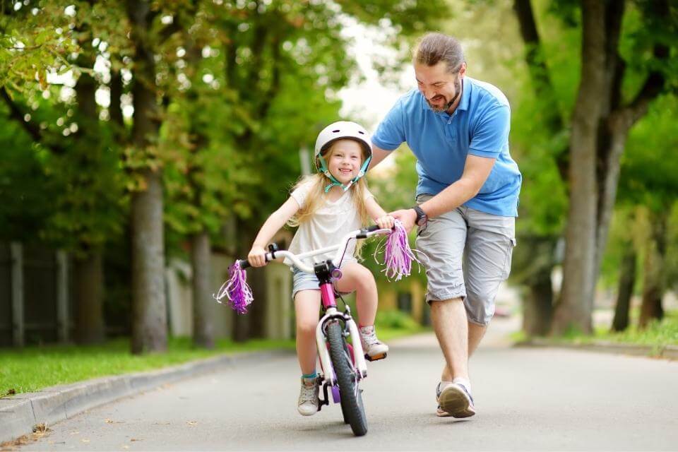 Dad running next to child learning to ride bike
