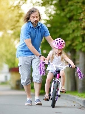 Dad running with child while teaching how to ride a bicycle