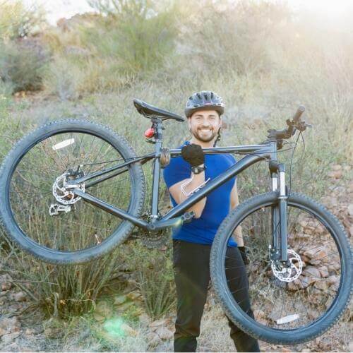 man holding mountain bike up with one hand