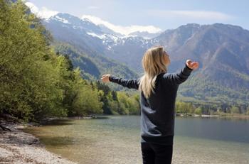 woman stretching beside lake and mountains