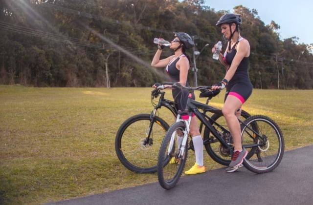 two women on bicycles taking a water break